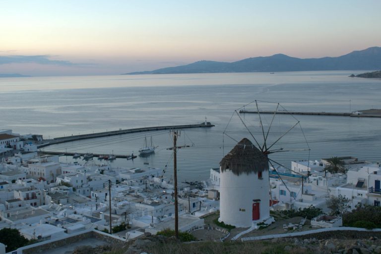 Sunset view over Mykonos Town white Cycladic buildings with iconic windmills